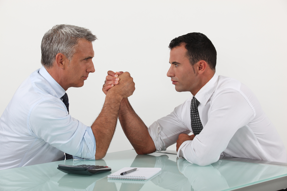 Businessmen arm wrestling old vs new